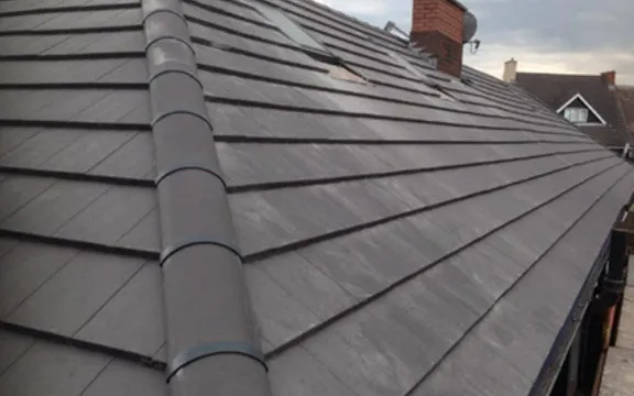 The roof of a house with a metal pipe sticking out of it.